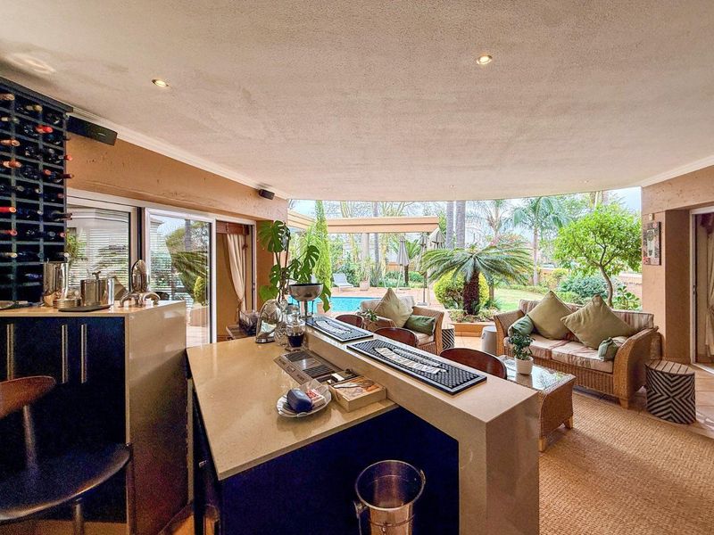 A well-appointed indoor bar area featuring a built-in counter, integrated wine storage, and seamless flow to the outdoor patio and pool area.