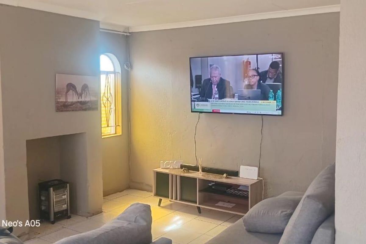 A living room featuring a built-in fireplace alcove, tiled flooring, and an arched window with security bars.