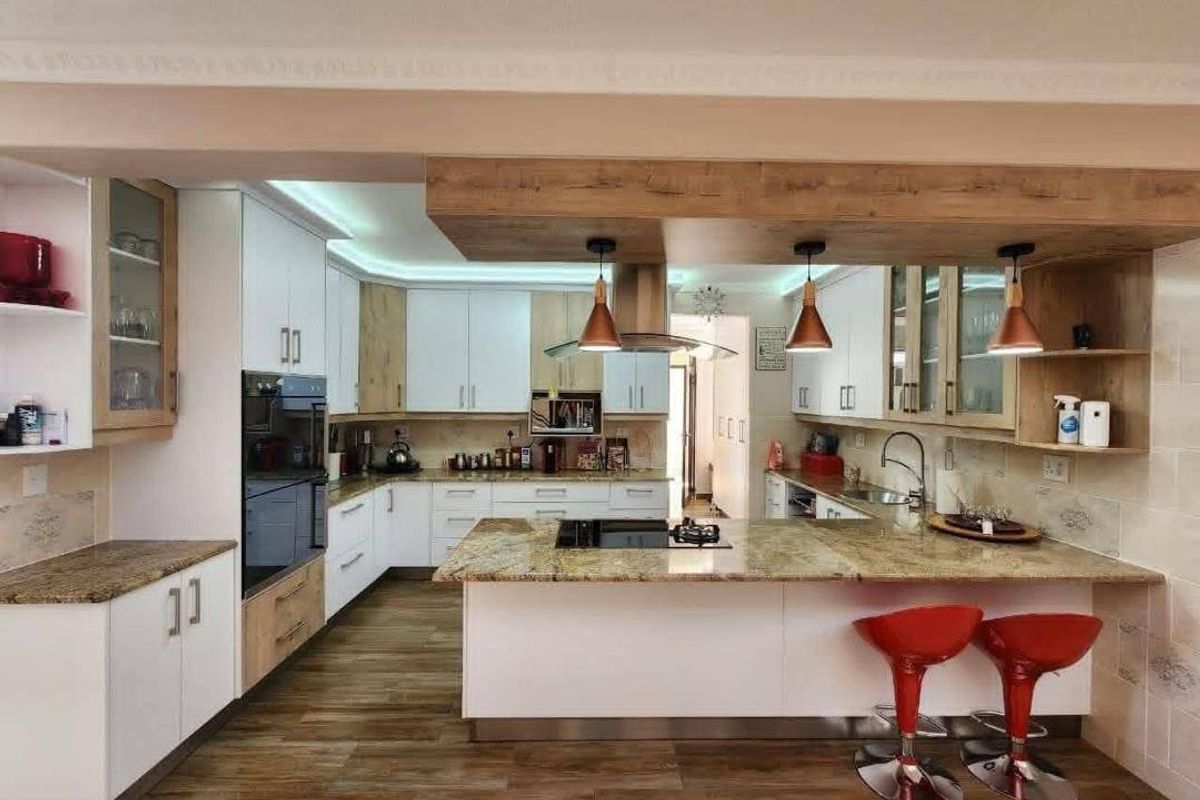 Modern kitchen featuring granite countertops, built-in oven, integrated hob, extractor fan, and contemporary cabinetry with under-cabinet and recessed lighting.