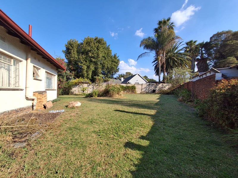 A spacious rear garden featuring a lawn area, enclosed by a combination of brick and precast concrete boundary walls.