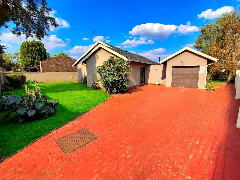 Front view of the property featuring a paved driveway, a single garage, and a well-maintained garden area.