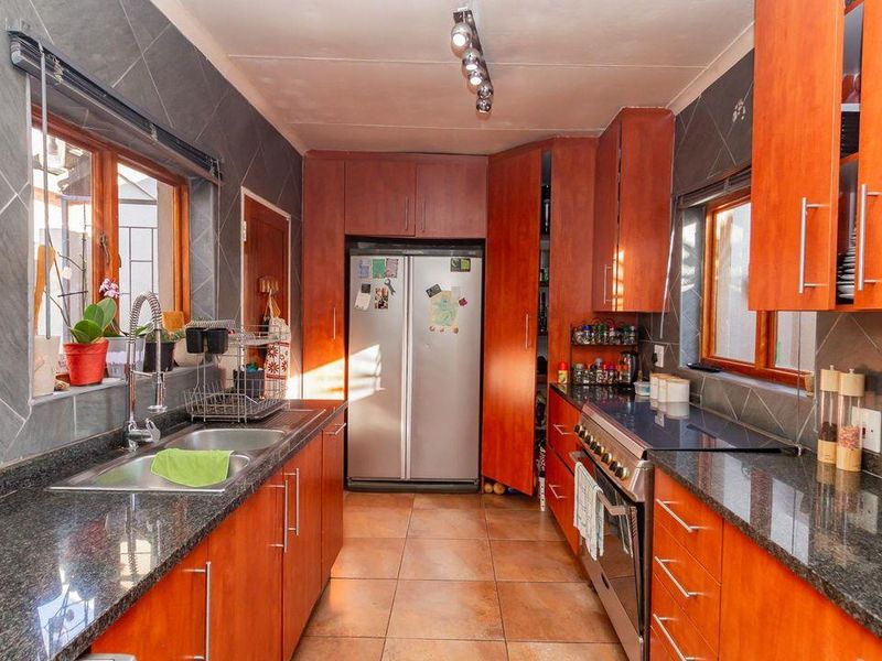 A functional kitchen featuring granite countertops, wooden cabinetry, tiled splashbacks, and a freestanding oven, offering a practical layout for daily cooking and preparation.