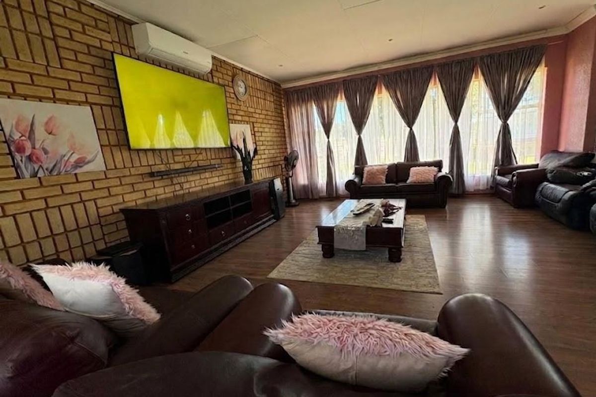 Spacious living room featuring a distinctive face-brick feature wall, laminate flooring, and a wall-mounted air conditioning unit.