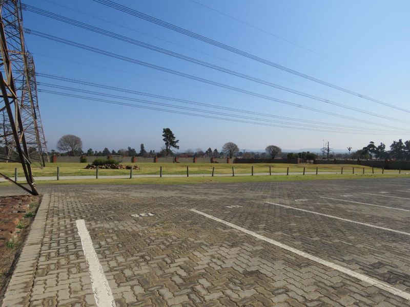 An open paved parking area with a perimeter wall and overhead power lines visible in the background.