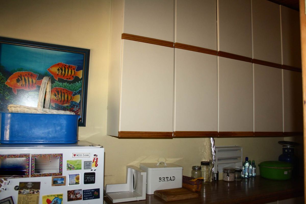 A kitchen area featuring cream-colored wall-mounted cabinetry with wood trim accents and a dark laminate countertop.