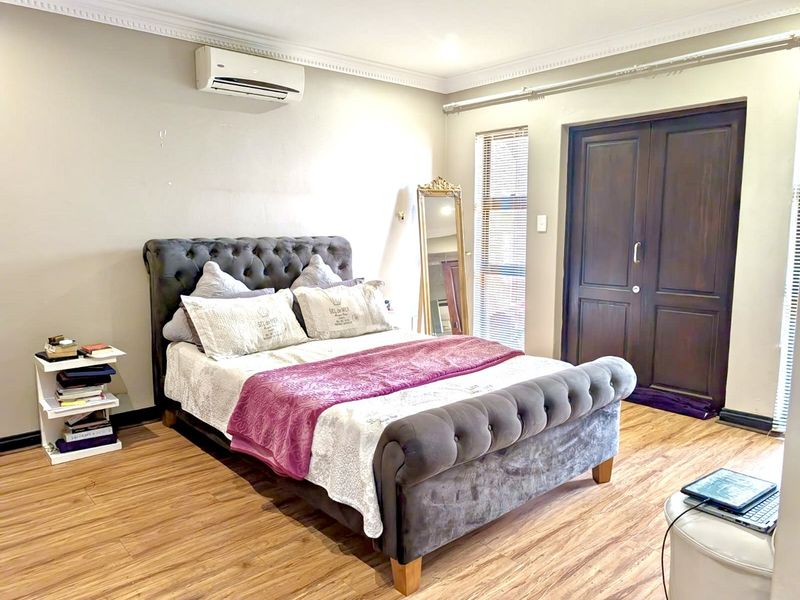 A bedroom featuring laminate flooring, a split-system air conditioner, and built-in storage cupboards.