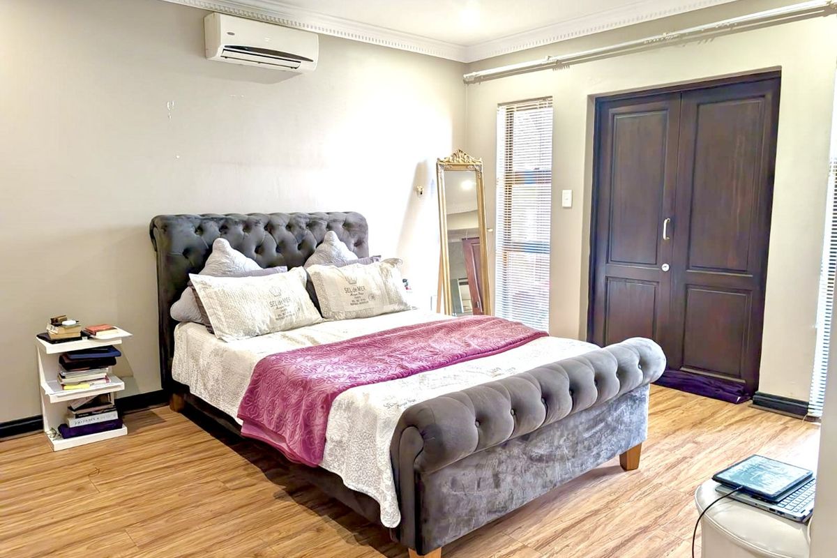 A bedroom featuring laminate flooring, a split-system air conditioner, and built-in storage cupboards.