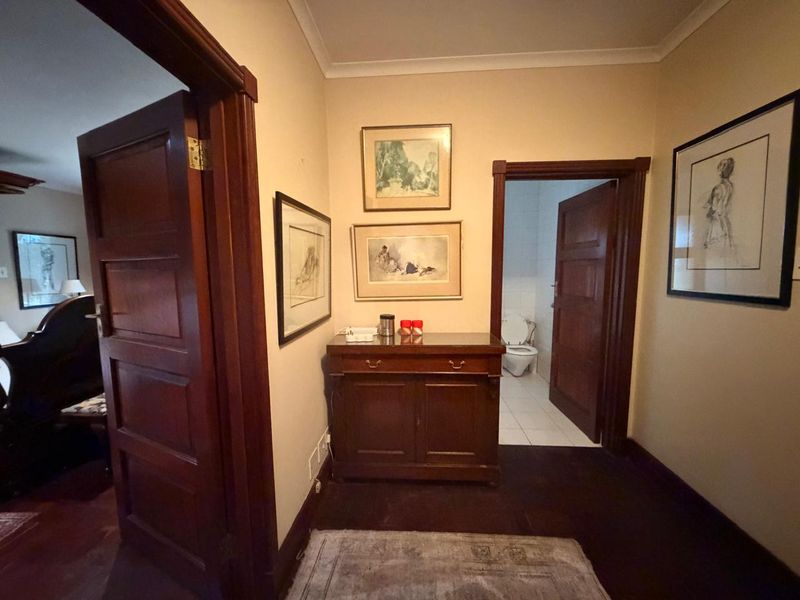 A well-maintained hallway featuring classic timber door frames and doors, providing access to adjacent rooms including a bathroom.