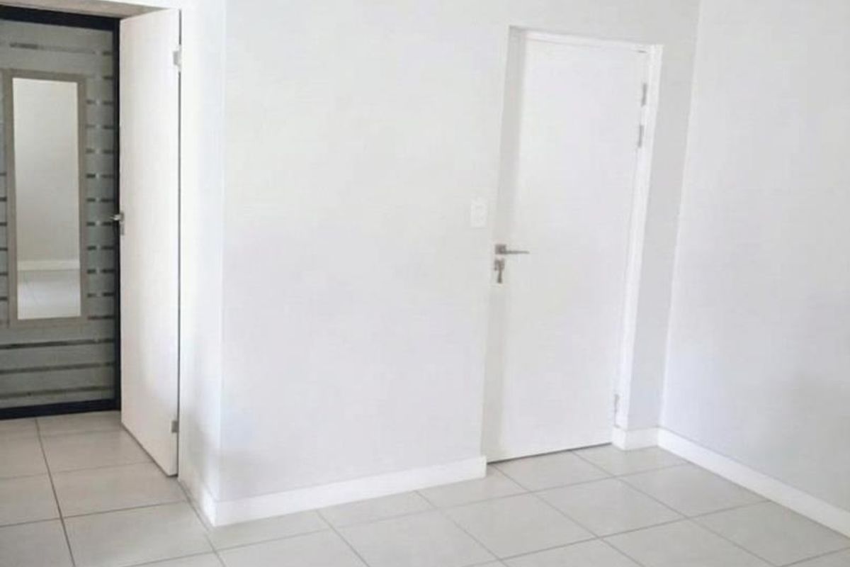 A bright, empty living area featuring neutral tiled flooring and clean white walls, providing a versatile blank canvas for interior design.