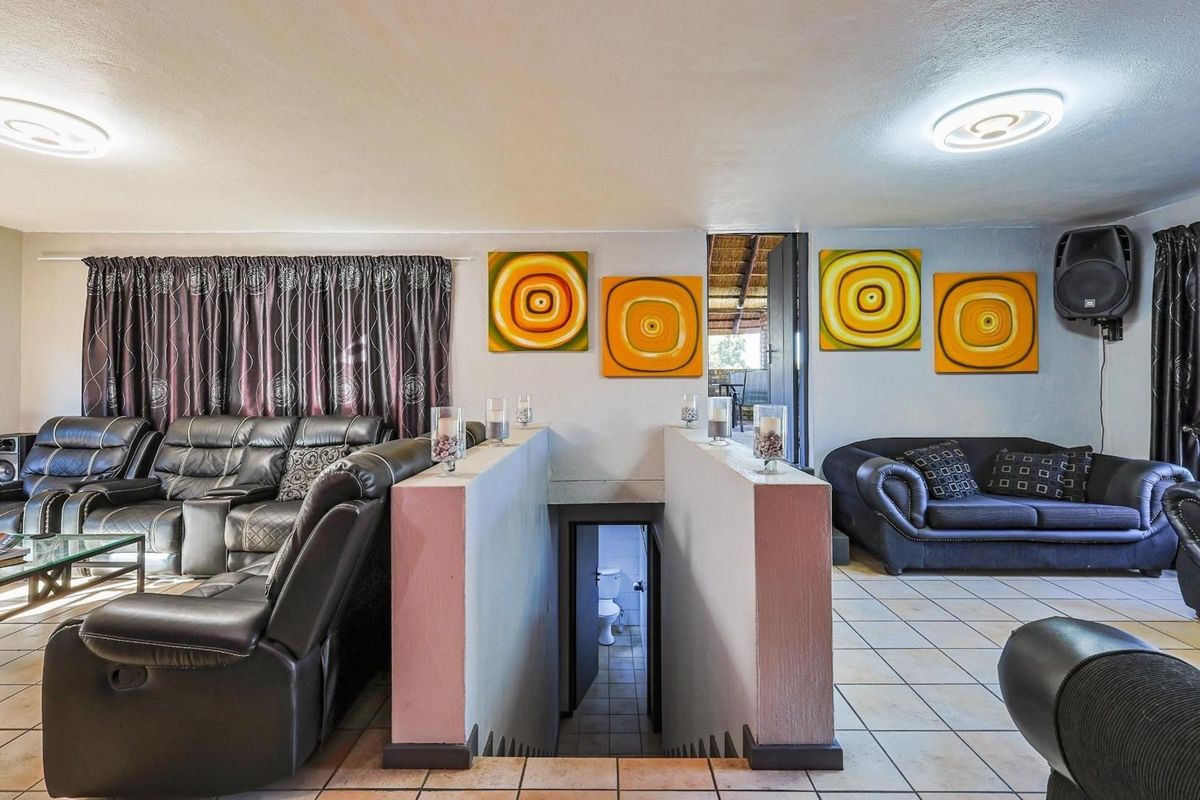 Spacious living area featuring tiled flooring, central staircase access, and dual seating zones with integrated lighting.