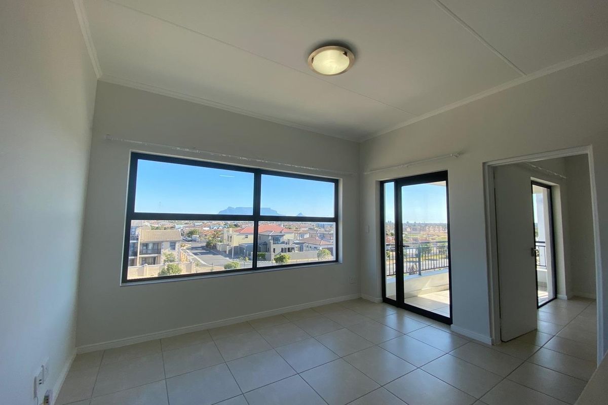 Bright living area featuring large windows with scenic views, tiled flooring, and direct access to a private balcony.