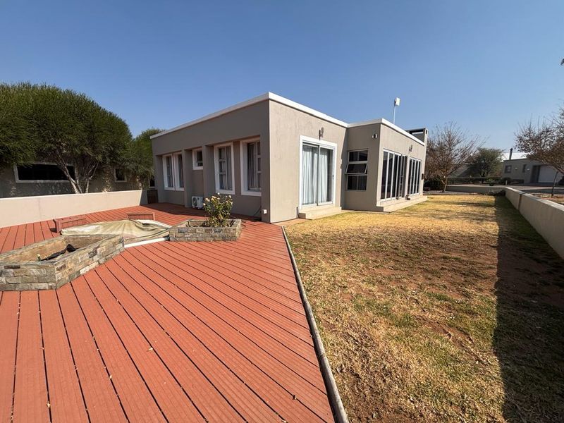 Rear exterior view featuring a composite deck with a stone-clad fire pit, sliding glass doors, and a spacious garden area.