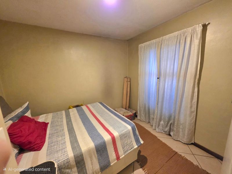 A standard bedroom featuring tiled flooring and neutral wall finishes, providing a functional space with natural light access.