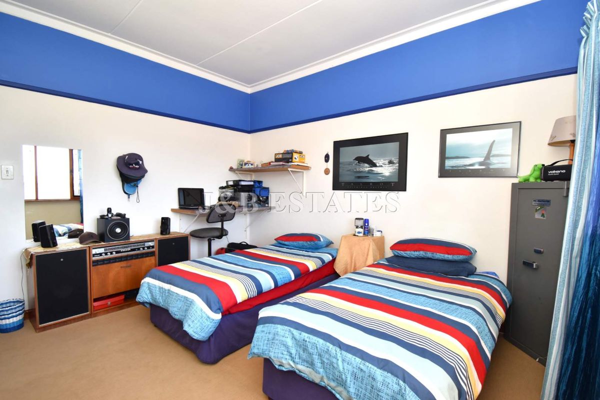 A bedroom featuring high ceilings with a decorative blue border, carpeted flooring, and a built-in wall shelf.
