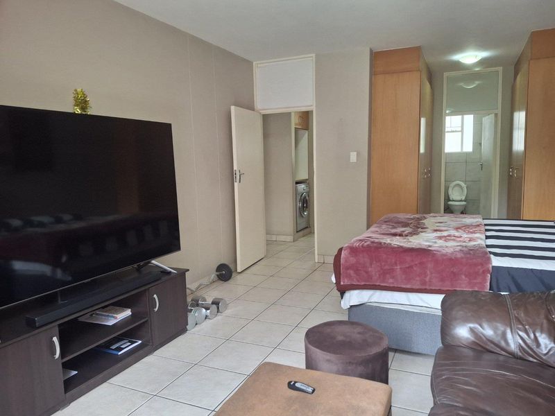 Spacious bedroom featuring built-in cupboards, tiled flooring, and an adjoining en-suite bathroom.