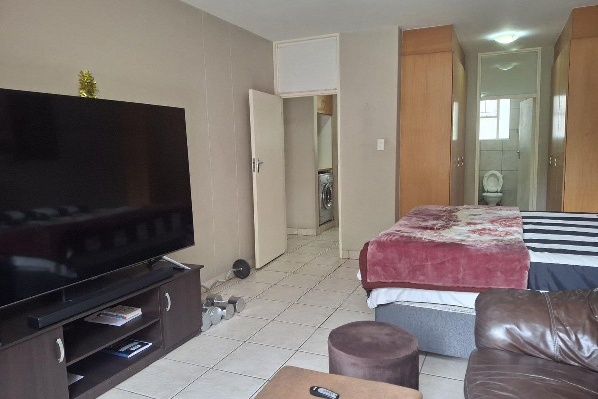 Spacious bedroom featuring built-in cupboards, tiled flooring, and an adjoining en-suite bathroom.
