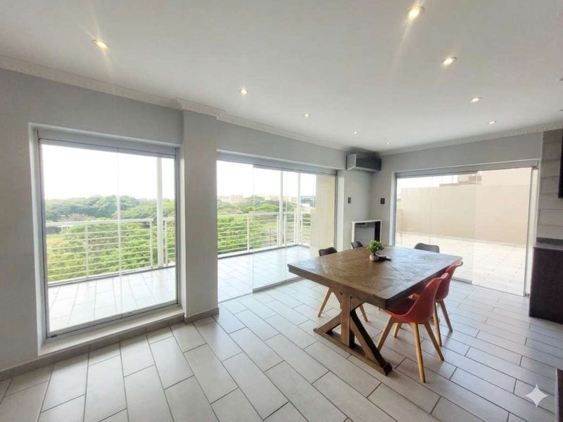 Spacious open-plan living and dining area featuring large sliding glass doors that open onto a balcony, providing ample natural light and scenic views.
