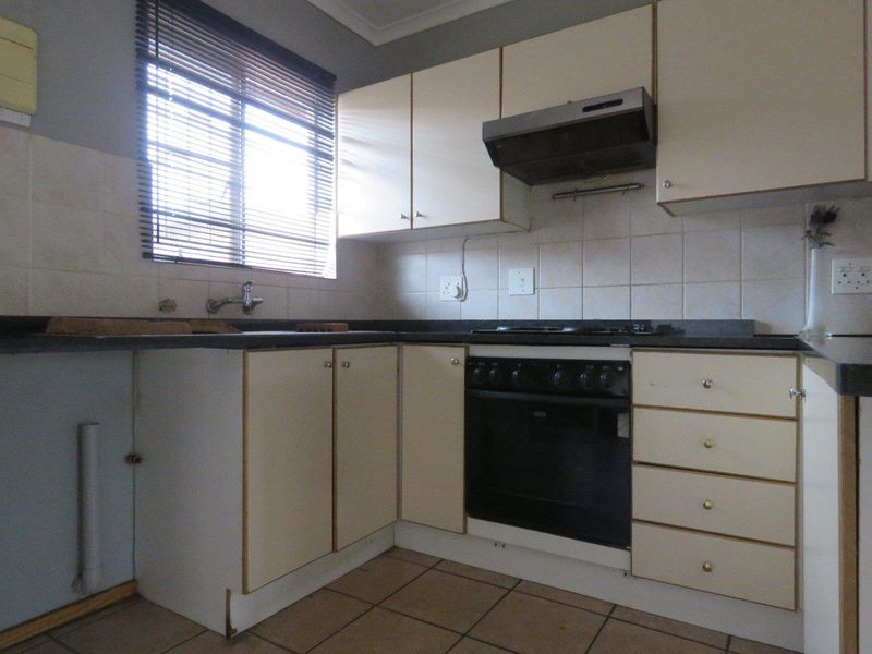 A functional kitchen featuring built-in cabinetry, a built-in oven with extractor fan, tiled backsplash, and tiled flooring, offering potential for modernization.