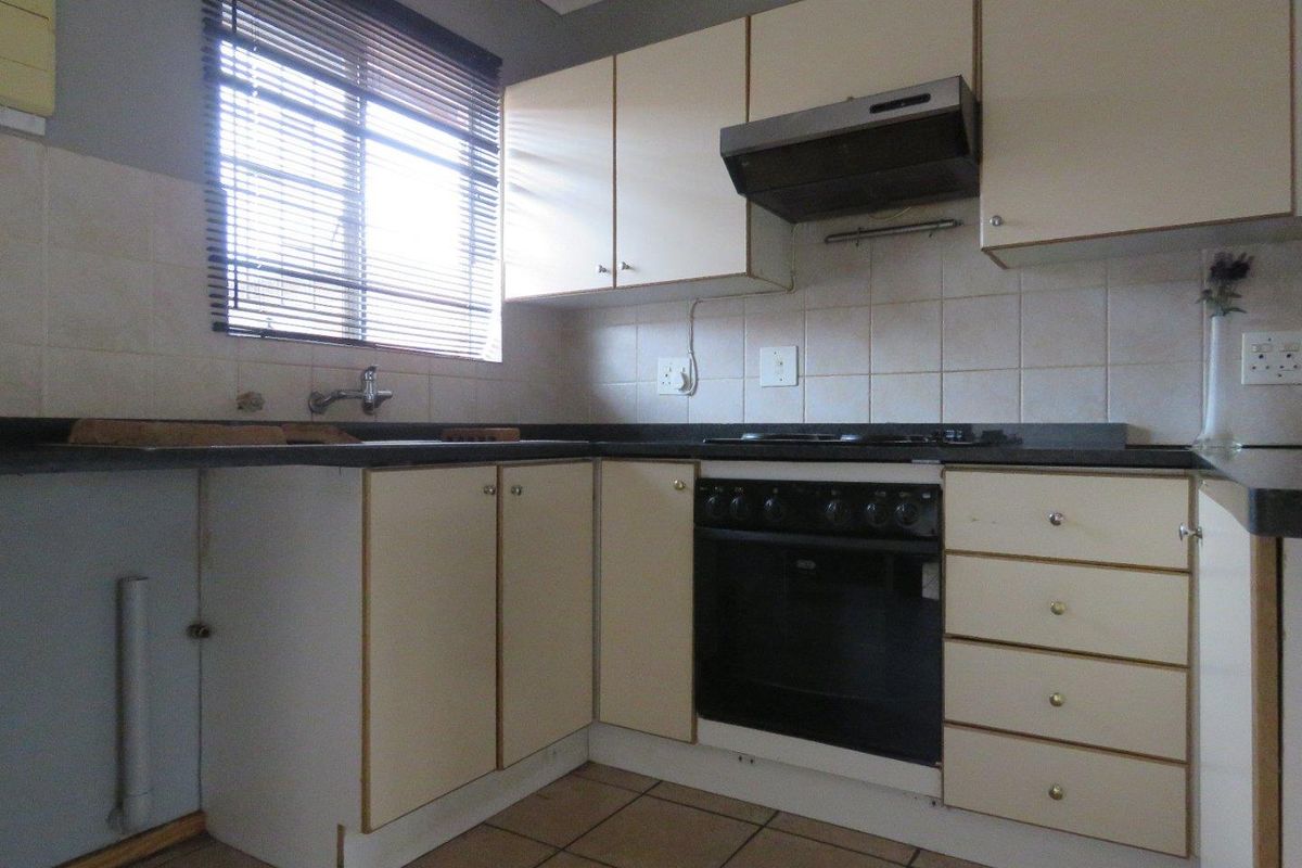 A functional kitchen featuring built-in cabinetry, a built-in oven with extractor fan, tiled backsplash, and tiled flooring, offering potential for modernization.