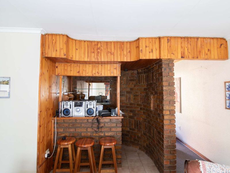 A dedicated bar area featuring a brick counter, timber paneling, and built-in mirror, offering a classic retro aesthetic.