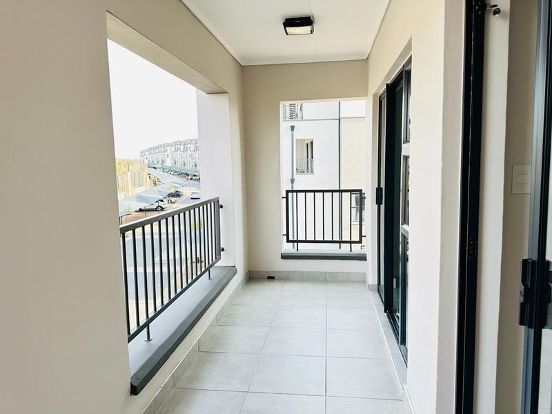 A clean, modern balcony featuring tiled flooring, secure metal balustrades, and sliding glass door access, offering a bright and functional outdoor space.