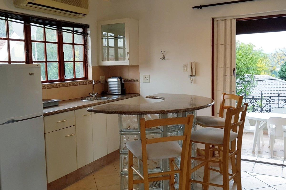 Compact kitchen featuring a breakfast bar with glass block base, tiled backsplash, and direct access to an outdoor balcony area.