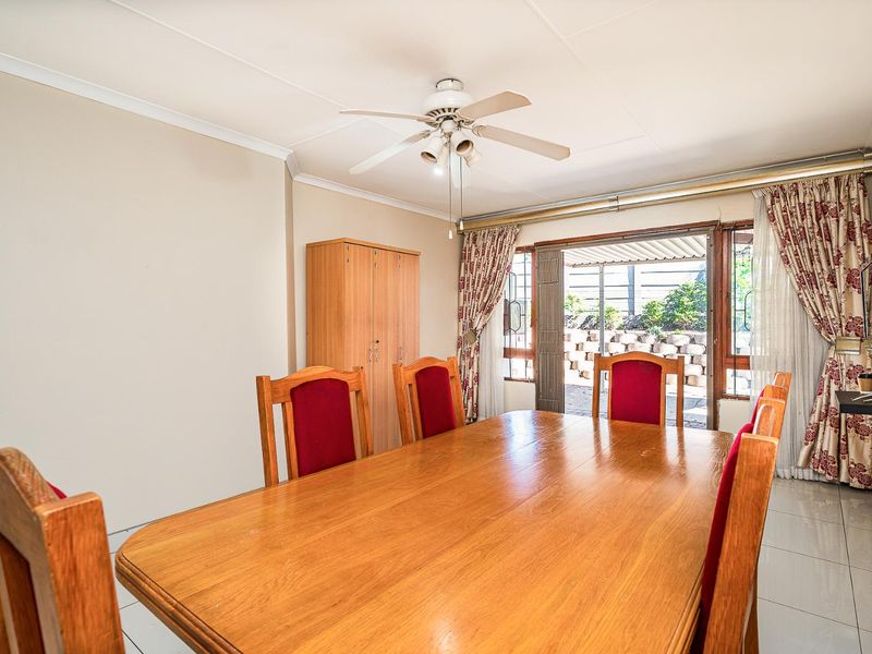 A dining room featuring tiled flooring, a ceiling fan, and a sliding glass door providing access to the outdoor patio area.