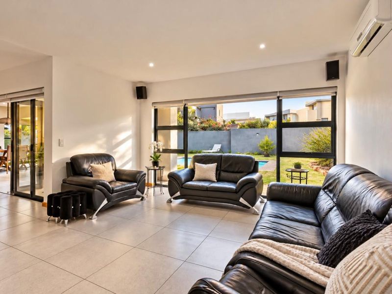 Spacious living room featuring large sliding glass doors that provide natural light and direct access to the outdoor pool and garden area.