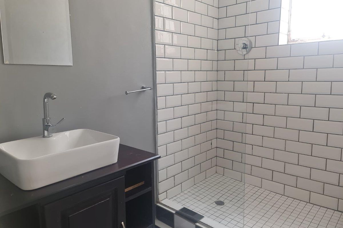 Modern bathroom featuring a walk-in shower with white subway tiles, a glass partition, and a contemporary vessel sink vanity.