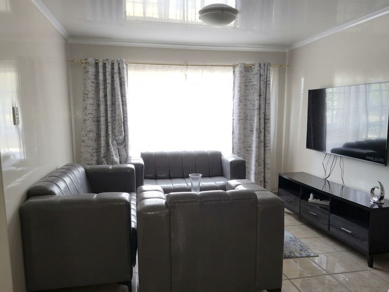 A living room featuring glossy ceiling finishes and tiled flooring, providing a neutral base for interior design updates.