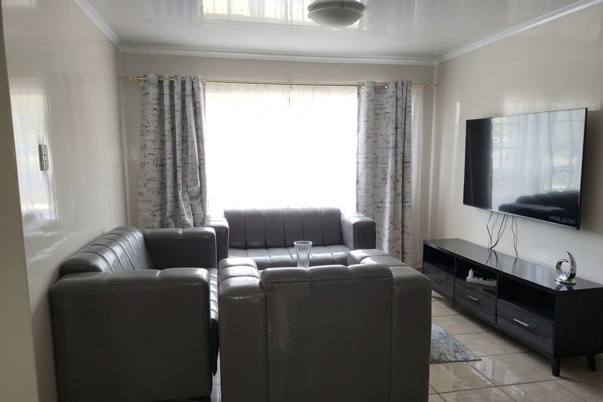 A living room featuring glossy ceiling finishes and tiled flooring, providing a neutral base for interior design updates.