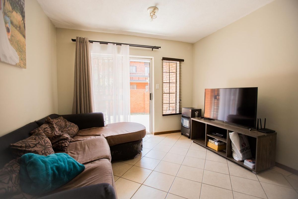 A comfortable living room featuring tiled flooring, a sliding glass door providing access to the exterior, and built-in window treatments.