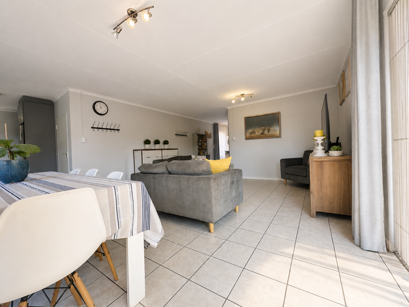 Spacious open-plan living and dining area featuring neutral tiled flooring, modern ceiling lighting, and large sliding glass doors providing natural light.