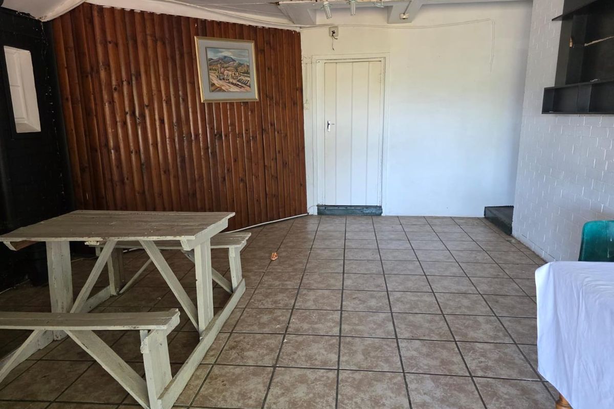 An interior space featuring tiled flooring, wood-paneled accent wall, and a single door, currently in need of maintenance and cosmetic updates.