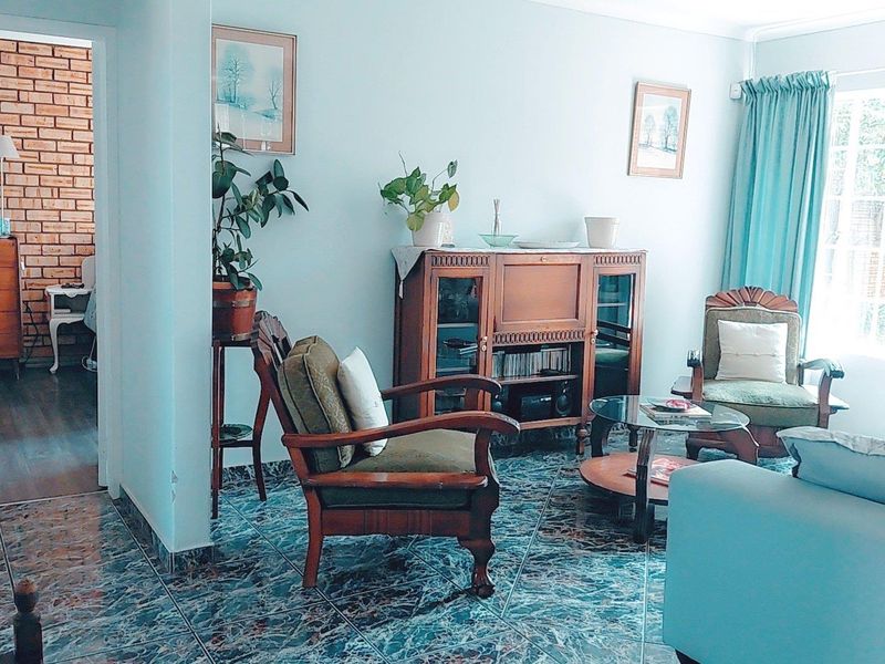 A living room featuring tiled flooring and access to an adjacent room, with natural light provided by a large window.