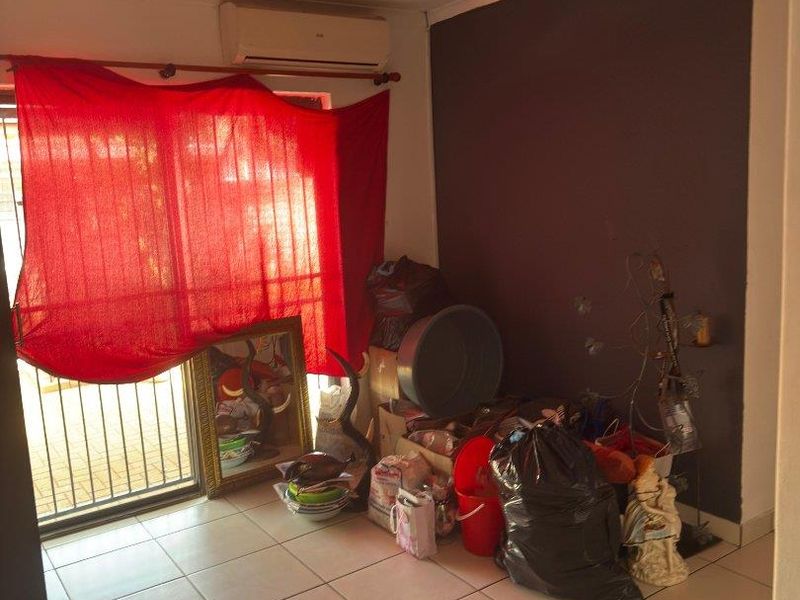 A living area featuring tiled flooring, a split-system air conditioner, and a sliding glass door with security gate access to the exterior.