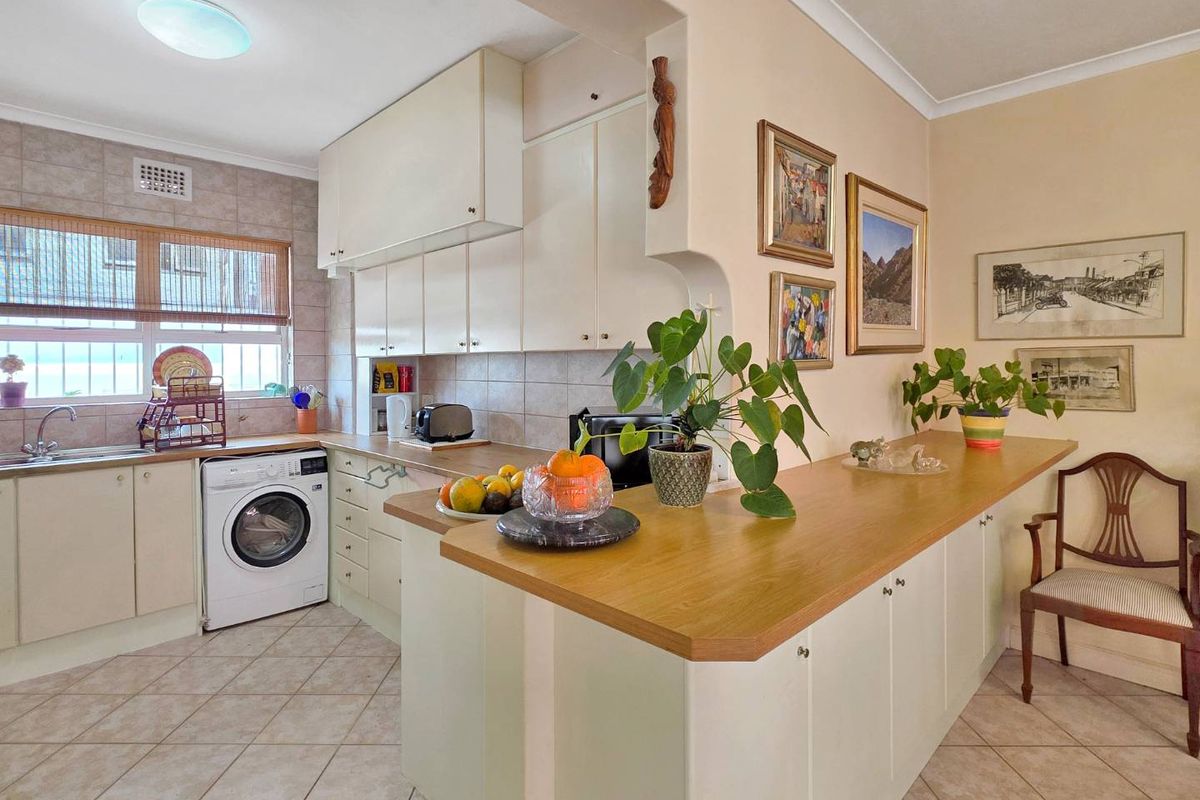 A functional kitchen featuring ample built-in cabinetry, a breakfast bar, tiled flooring, and a convenient integrated washing machine.