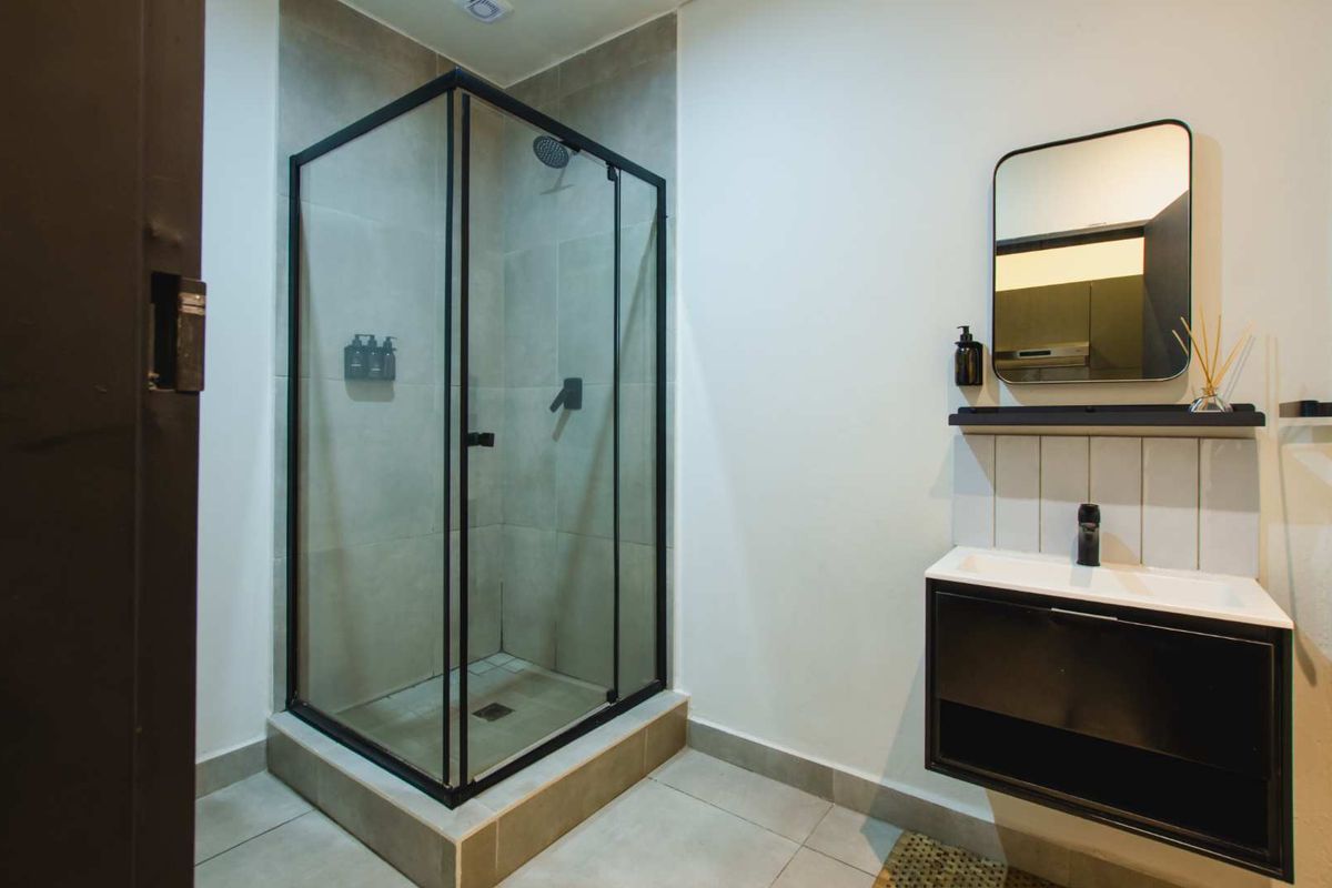 Modern bathroom featuring a sleek glass-enclosed shower with black frame, contemporary vanity unit, and minimalist fixtures.