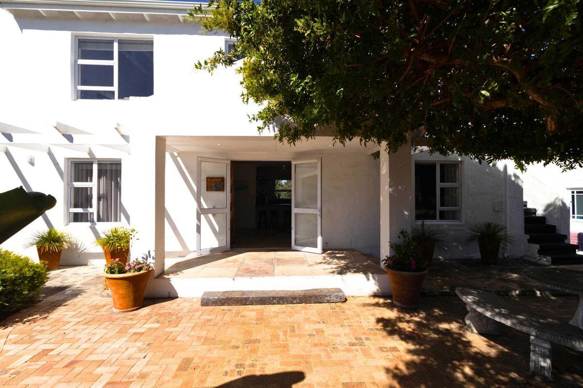 A rear view of the house featuring a covered patio area with brick paving, leading into the interior living space.