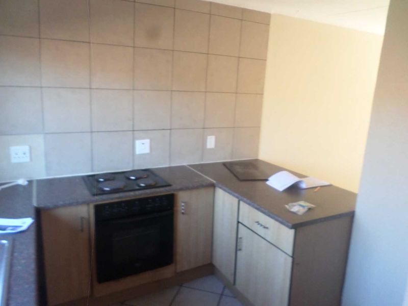 A functional kitchen area featuring built-in cabinetry, a fitted oven and hob, and tiled splashback finishes.