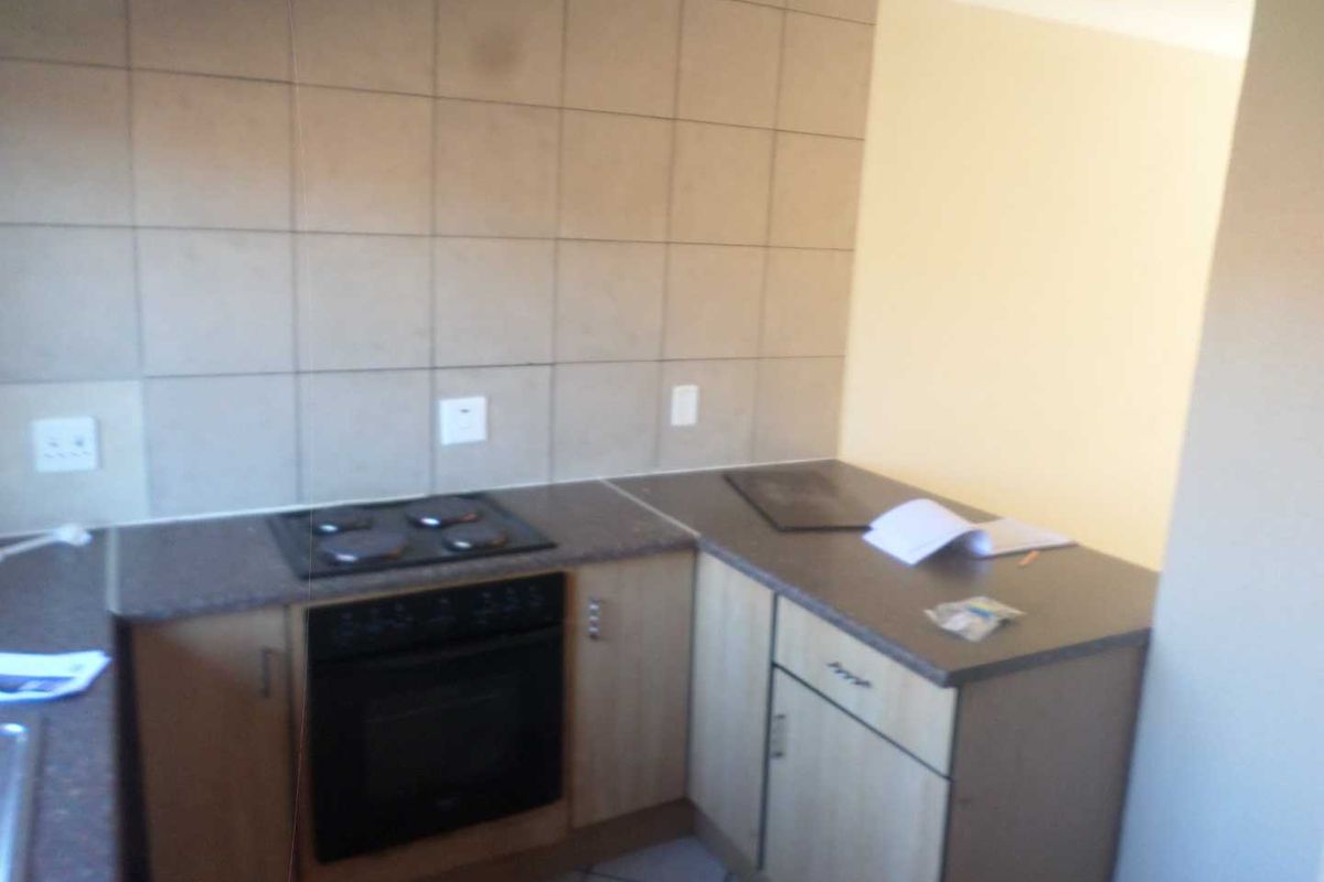 A functional kitchen area featuring built-in cabinetry, a fitted oven and hob, and tiled splashback finishes.