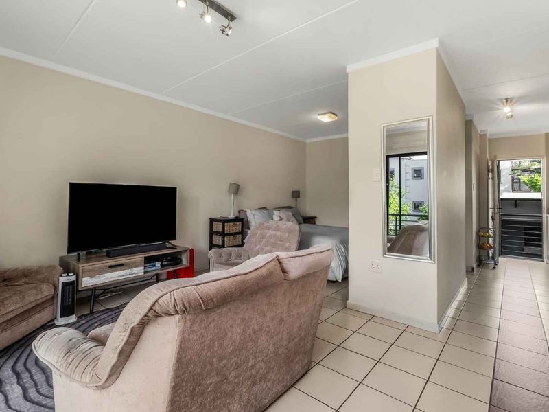Open-plan living area featuring tiled flooring, integrated kitchen cabinetry, and direct access to an outdoor balcony space.