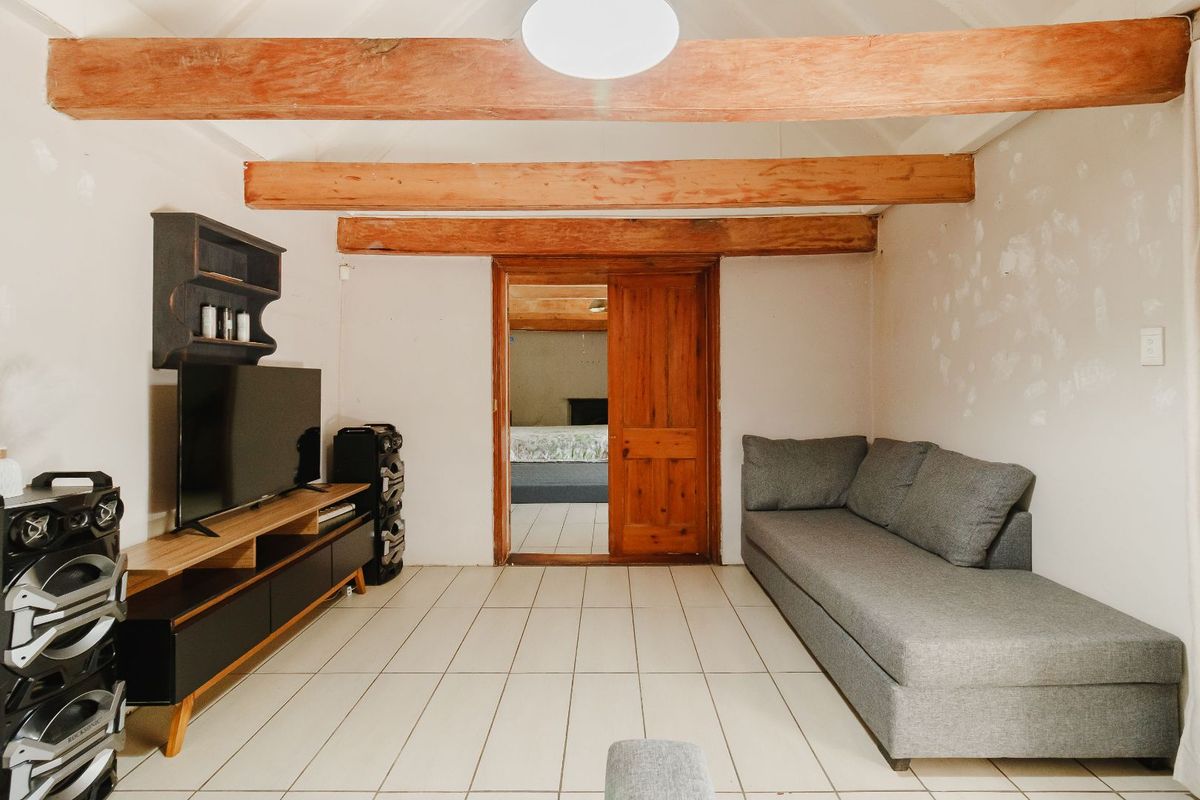 Living area featuring exposed timber ceiling beams, tiled flooring, and a wooden sliding door leading to an adjacent room.