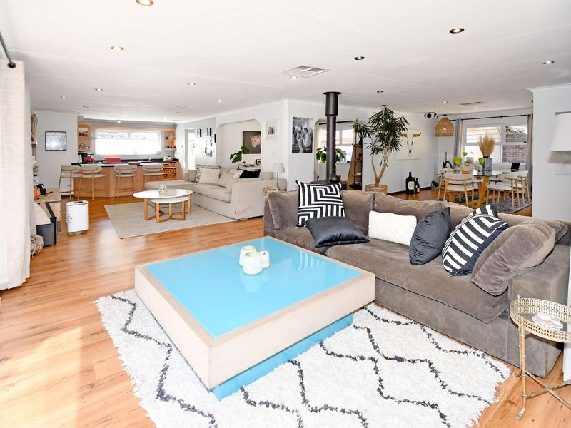 Spacious open-plan living area featuring a modern kitchen island, wood-burning fireplace, and light laminate flooring, creating a bright and functional family space.