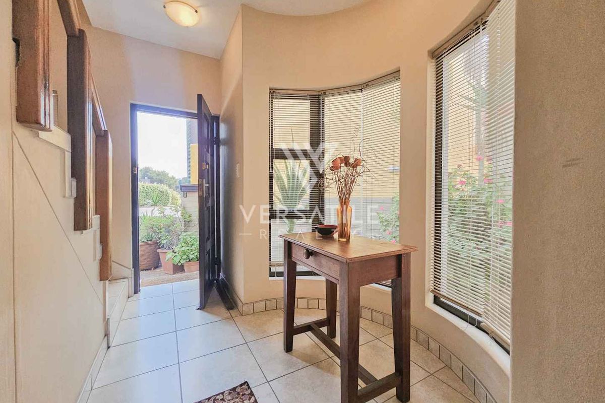 A bright entrance hall featuring tiled flooring, a staircase, and a large bay window that allows for natural light.