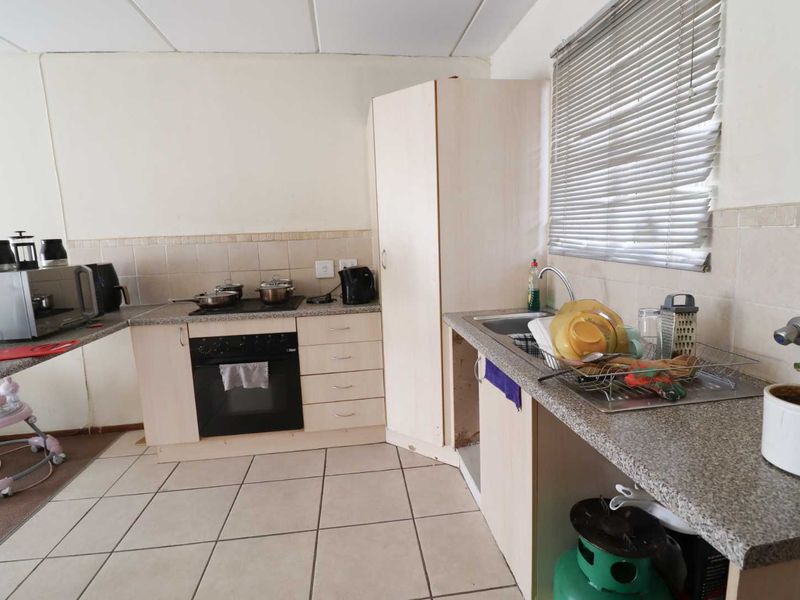 A functional kitchen featuring built-in cabinetry, granite countertops, a built-in oven, and tiled flooring. The space requires minor repairs and cosmetic updates.