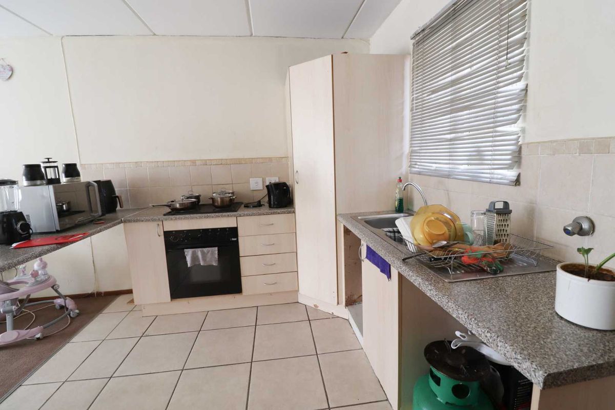 A functional kitchen featuring built-in cabinetry, granite countertops, a built-in oven, and tiled flooring. The space requires minor repairs and cosmetic updates.