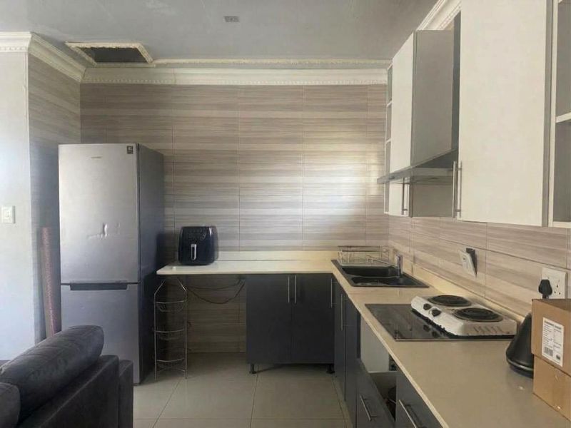 A functional kitchen featuring modern cabinetry, tiled splashbacks, a built-in hob, and an extractor fan, though the ceiling requires minor repair.