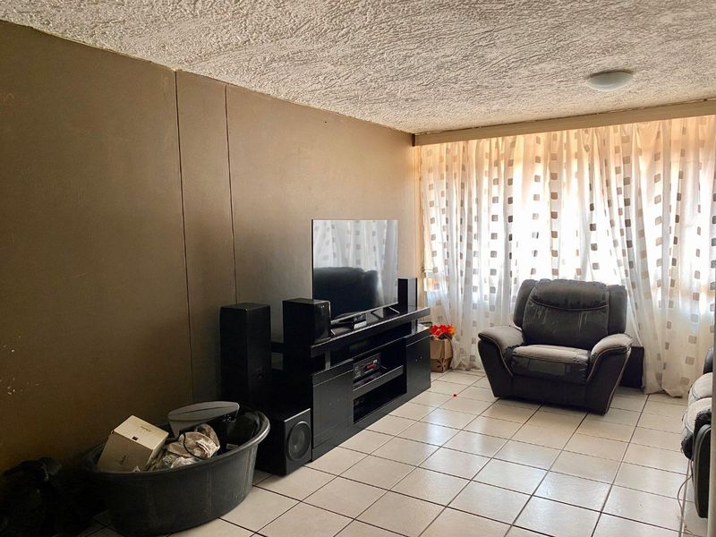 A living room featuring tiled flooring and a textured ceiling, offering a functional space ready for modernization and aesthetic updates.