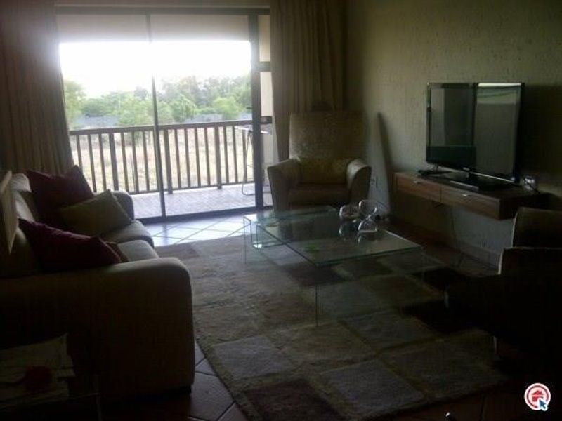 A living room featuring tiled flooring, a floating media console, and a large sliding glass door providing access to an outdoor balcony.